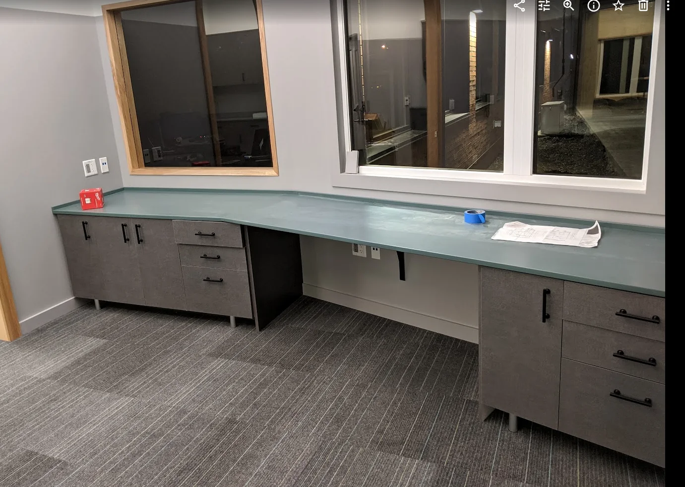 Installed gray cabinetry and long work counter beneath windows