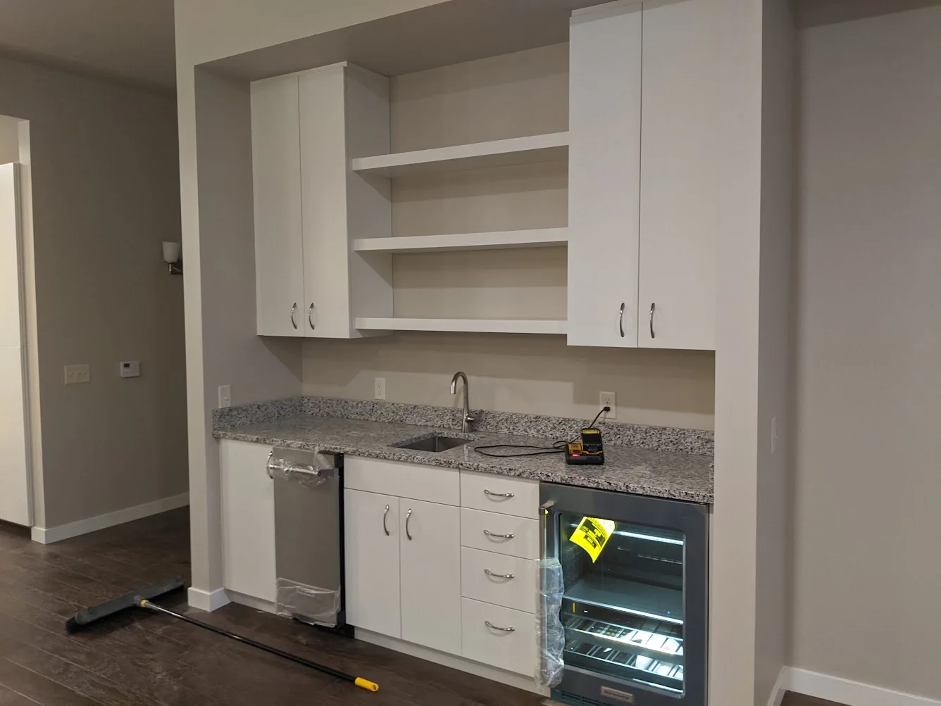 White built-in beverage bar with cabinets, open shelving, sink, and stone countertop